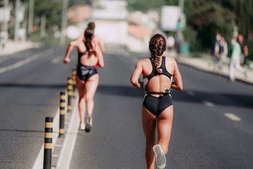 Free Faceless sportswomen running on asphalt road in daytime Stock Photo