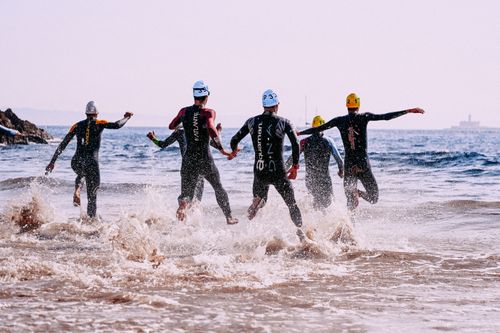 Free Full body of group of faceless people in suit for bathing running into wavy ocean in sunlight Stock Photo