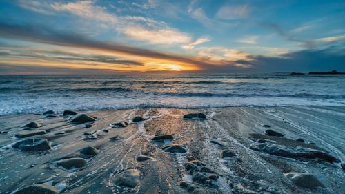 Free A tranquil seascape at sunset with waves gently lapping against the sandy shore. Stock Photo