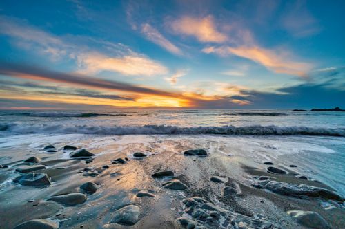 Free Vivid sunset over a rocky beach with crashing waves, captured in stunning detail. Stock Photo