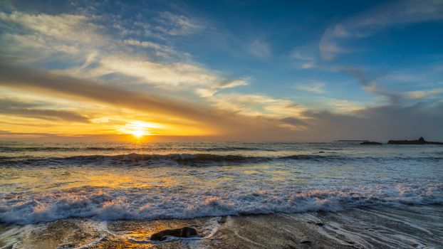 Beautiful sunset over the ocean waves at a peaceful beach scene.