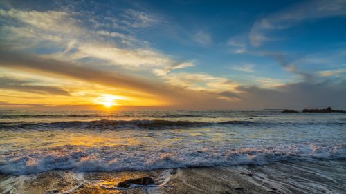 Free Beautiful sunset over the ocean waves at a peaceful beach scene. Stock Photo