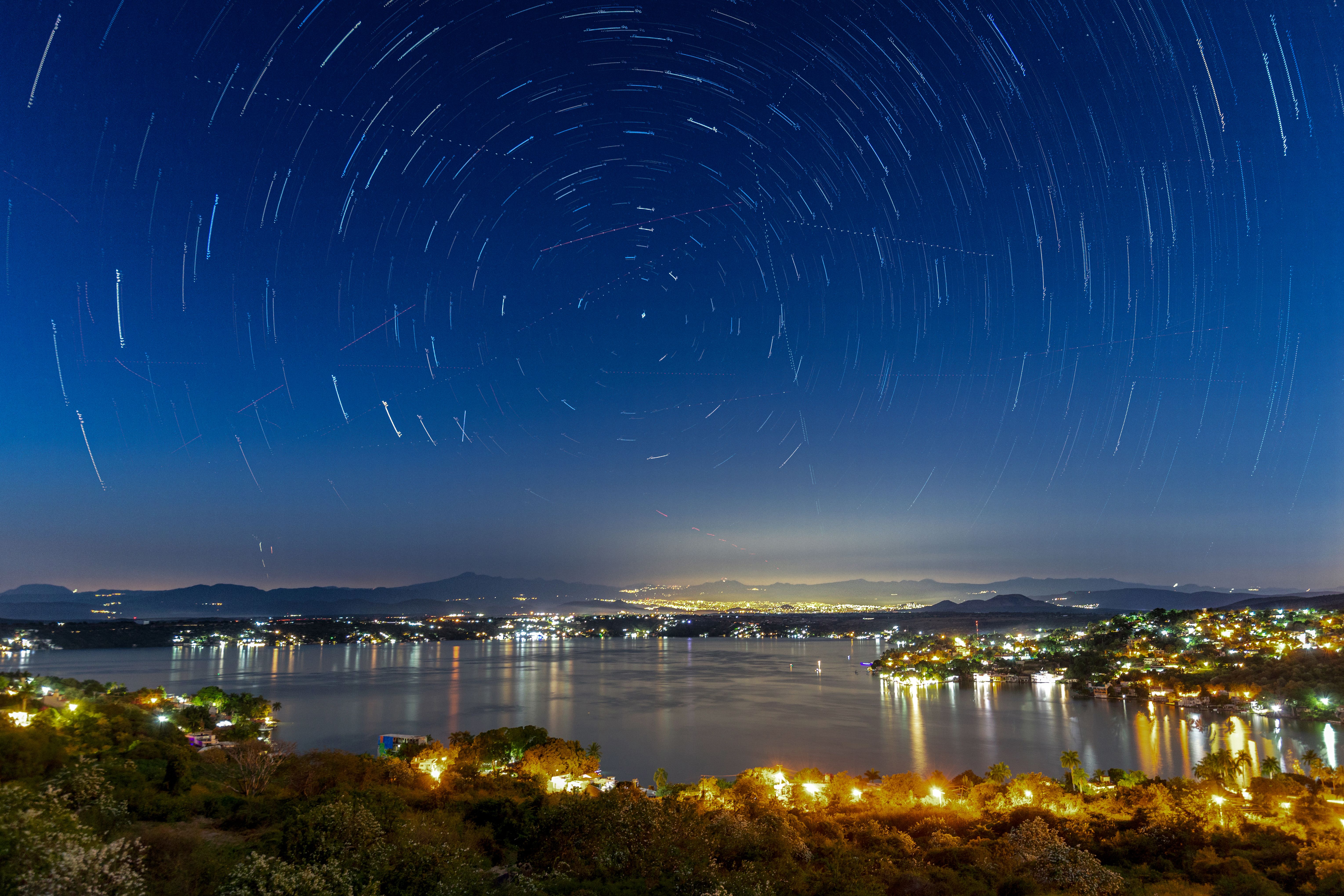 长时间曝光拍摄的城市与湖泊上空的星迹，展现了一个充满活力的夜空