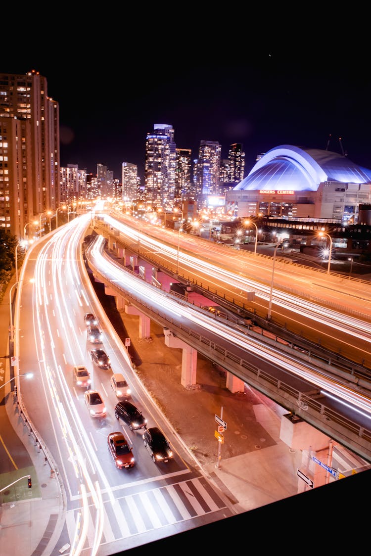 Traffic On Junction Roads Behind Multistage Houses In Night Town