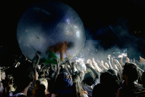 Crowd of unrecognizable people raising water ball with person