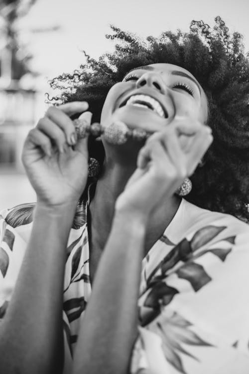 Free Black and white of young happy ethnic female in beads and trendy apparel laughing with closed eyes Stock Photo