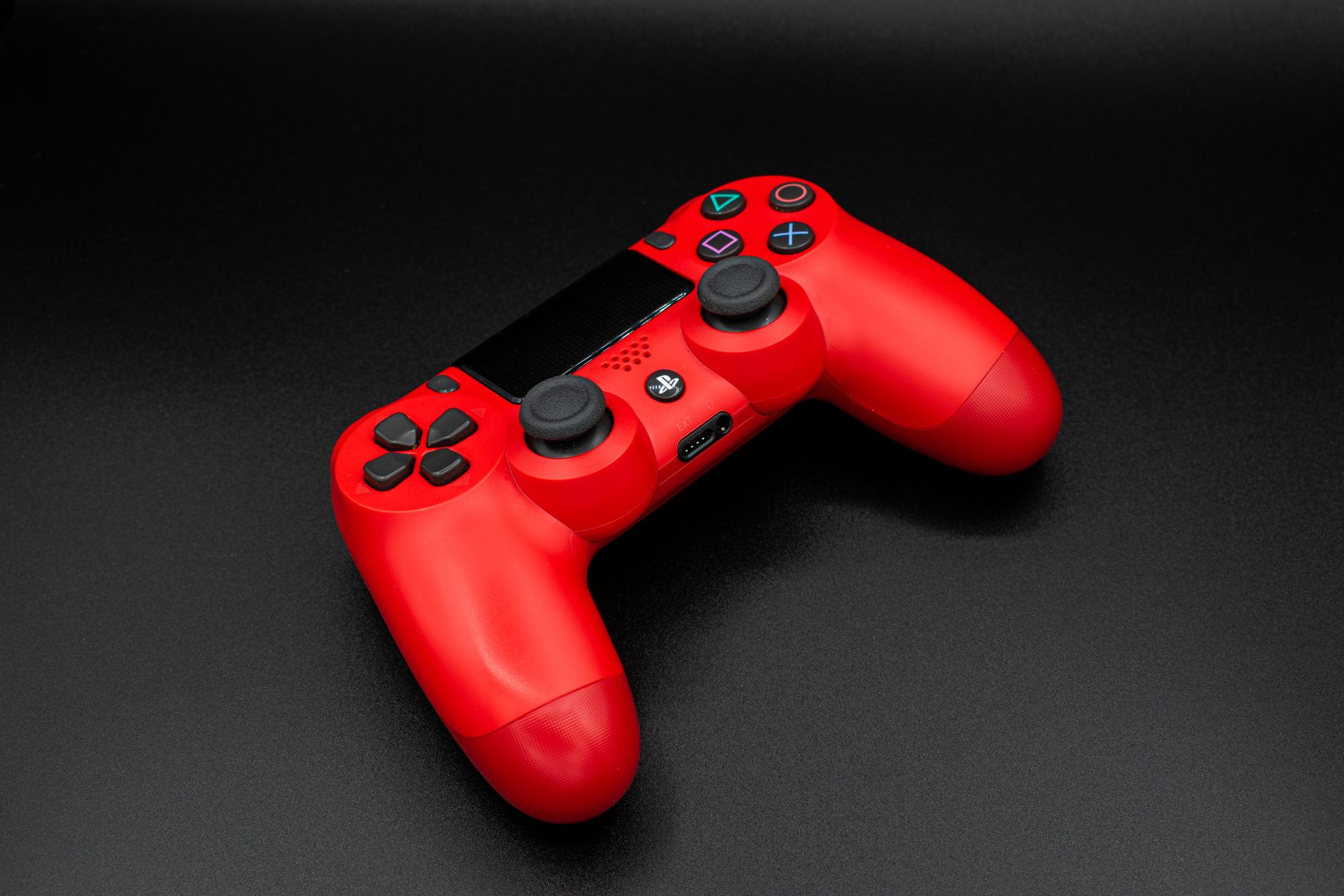 Close-up of a red game controller against a black surface, perfect for gaming themes.