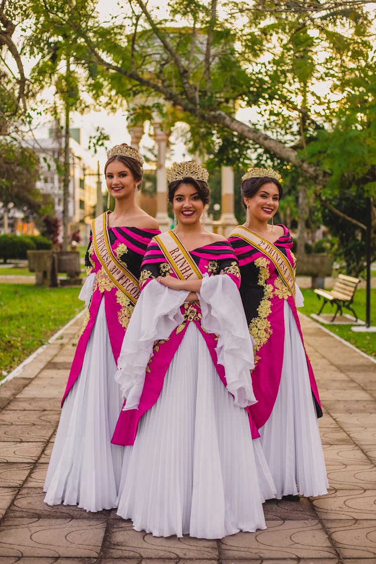 Women In Traditional Gowns With Crowns