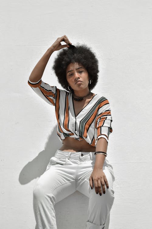 Stylish African American woman with comb near concrete wall