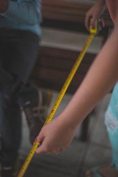 Close-up image of hands measuring with a yellow tape, capturing precision and focus.
