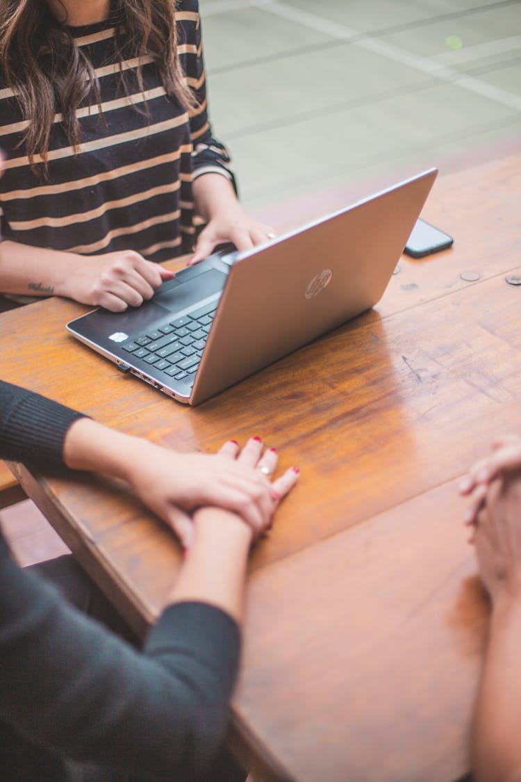 Person Using Laptop On Wooden Table