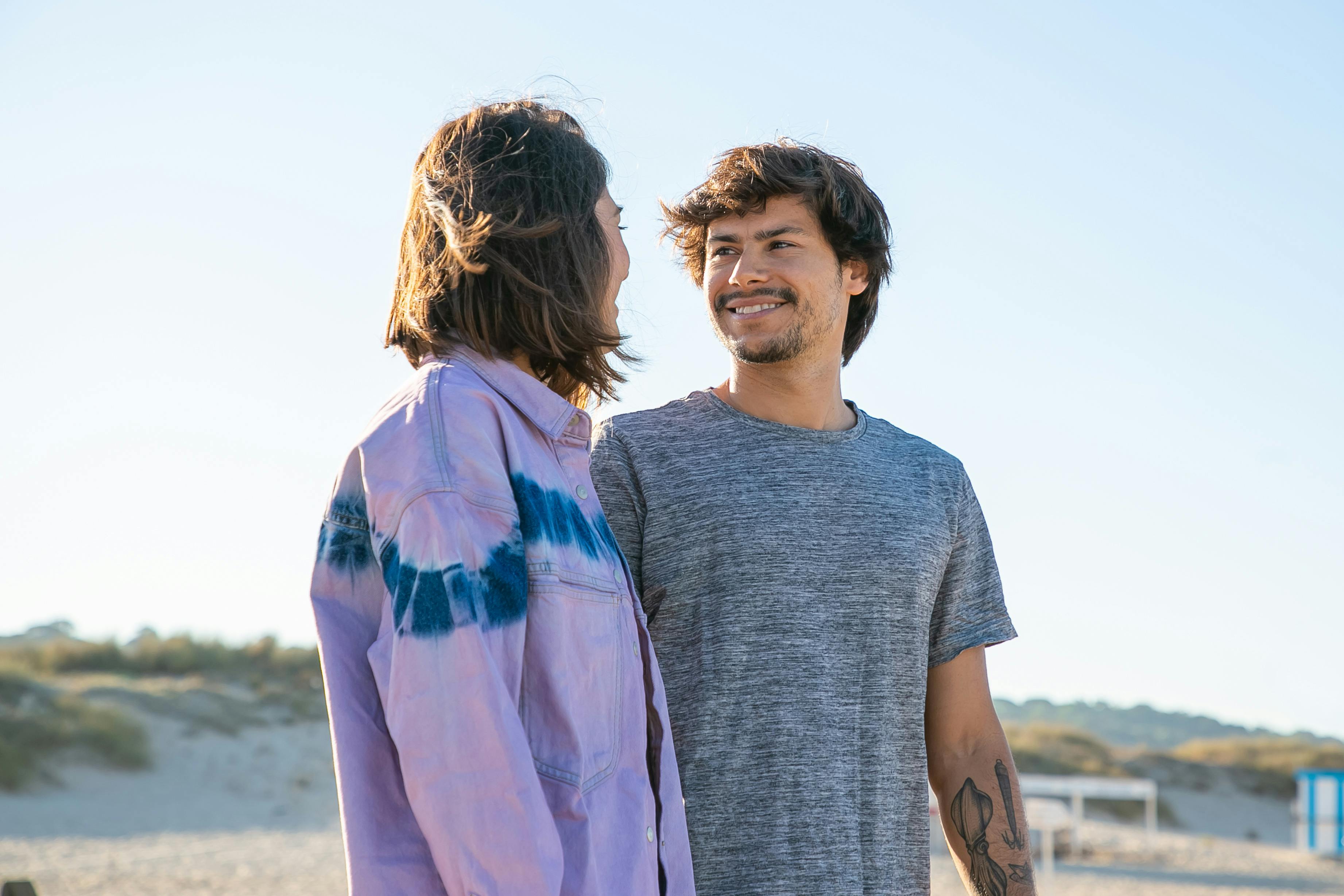 Young couple enjoying a sunny day together on a scenic beach.