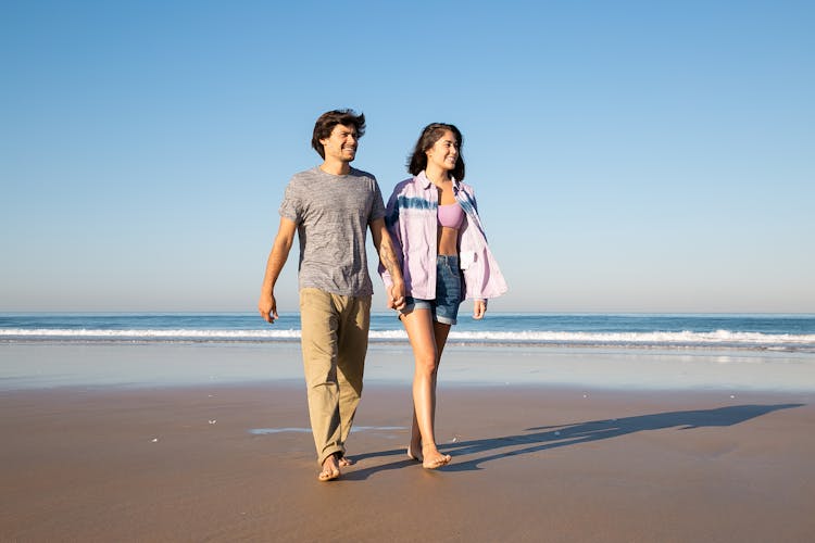 Couple Walking Barefoot On Sand