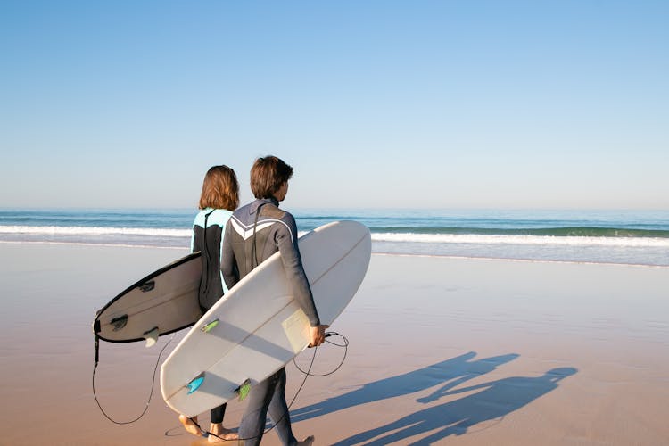 Couple Carrying Surfboards 