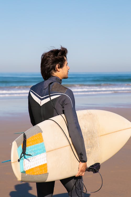 Man in Swimwear Carrying Surfboard