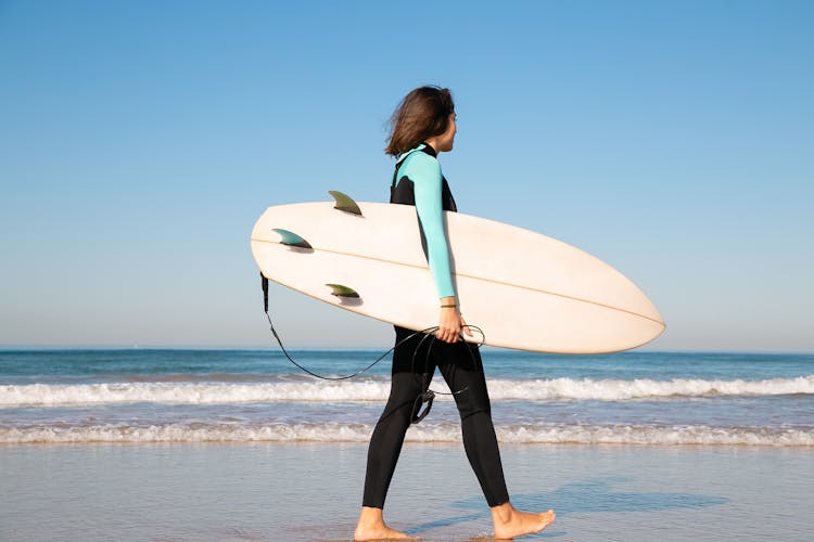 Person In Full Body Swimwear Carrying Surfboard