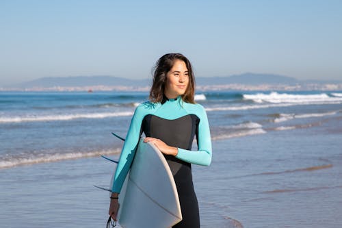 Woman in Swimwear Carrying Surfboard