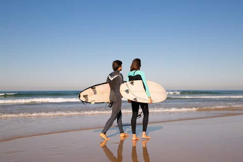 男人和女人抱着白色的冲浪板，在海滩上行走
