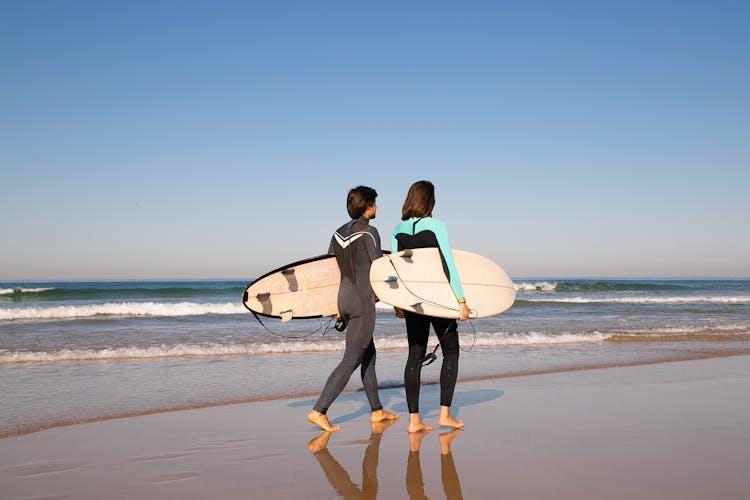 People Walking Barefoot On Shore