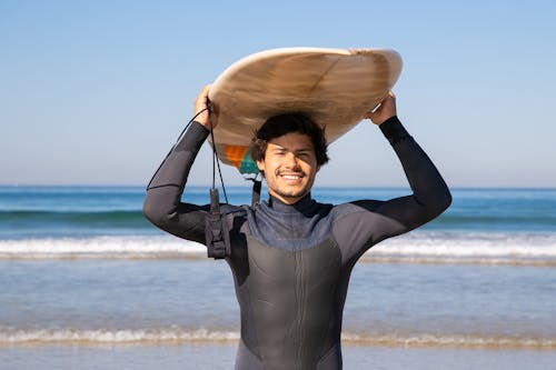 A Man in a Wetsuit Carrying a Surfboard