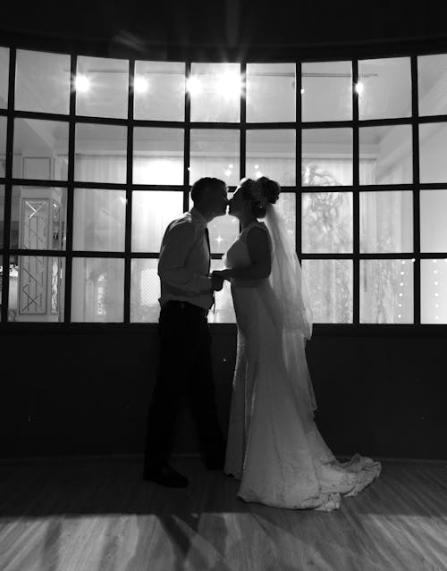 Bride and groom kissing against window