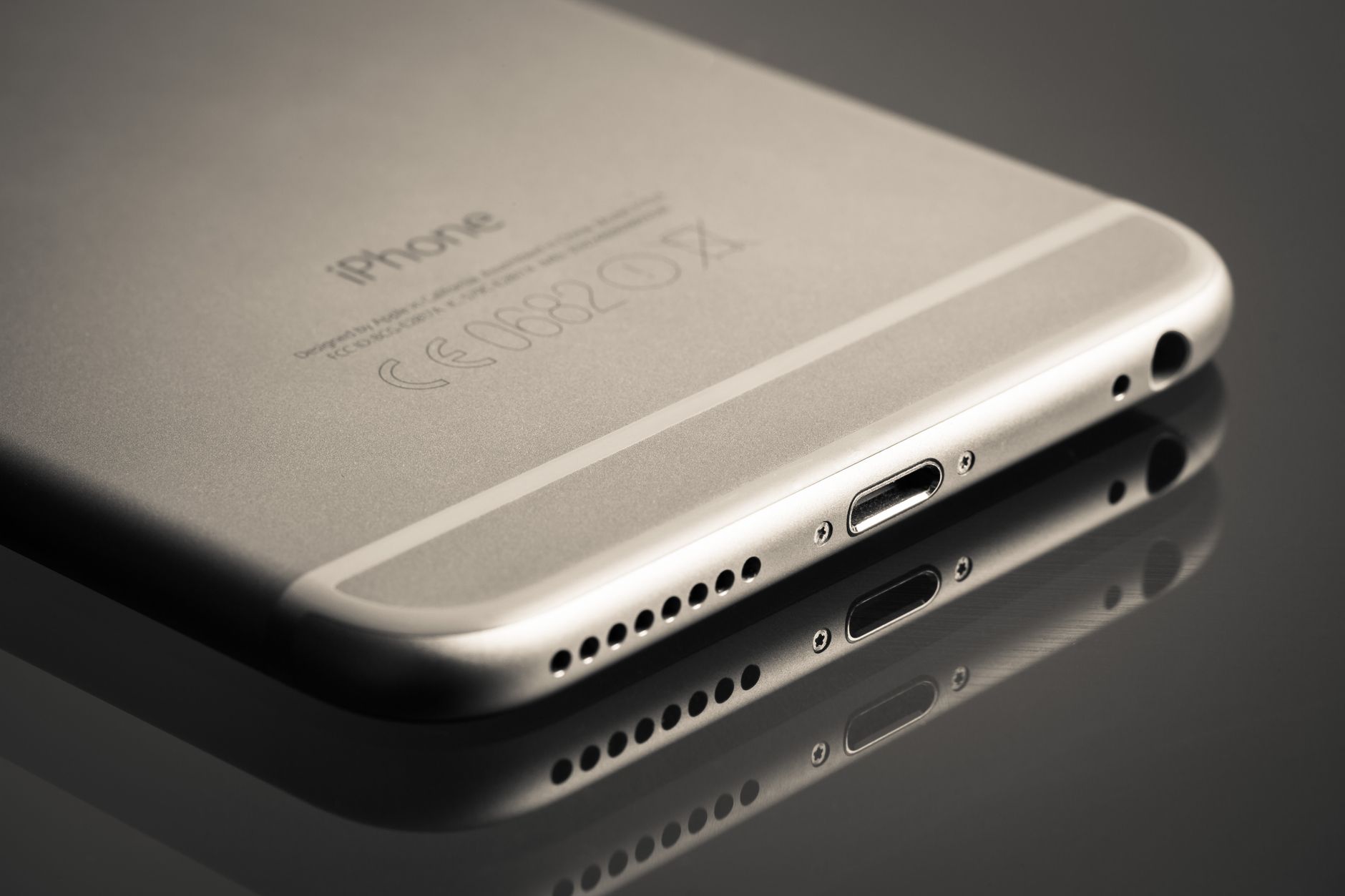 A sleek smartphone displayed at an angle showcasing its reflection on a smooth surface.