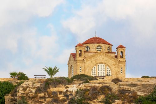 Free Scenic view of an Orthodox church on a cliff in Peyia, Paphos, Cyprus, under a cloudy sky. Stock Photo