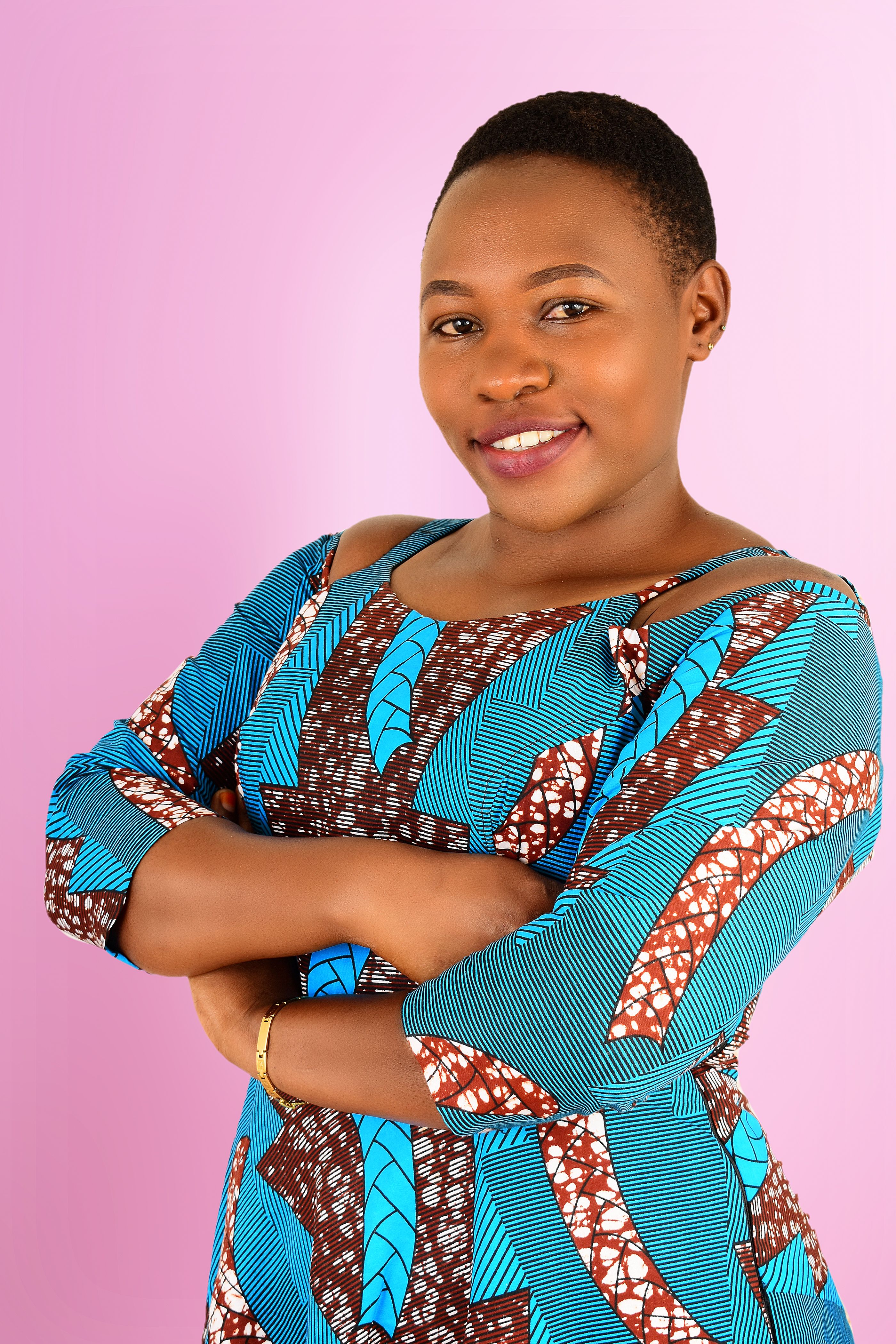 Portrait of a smiling woman in a colorful patterned dress against a soft pink background.