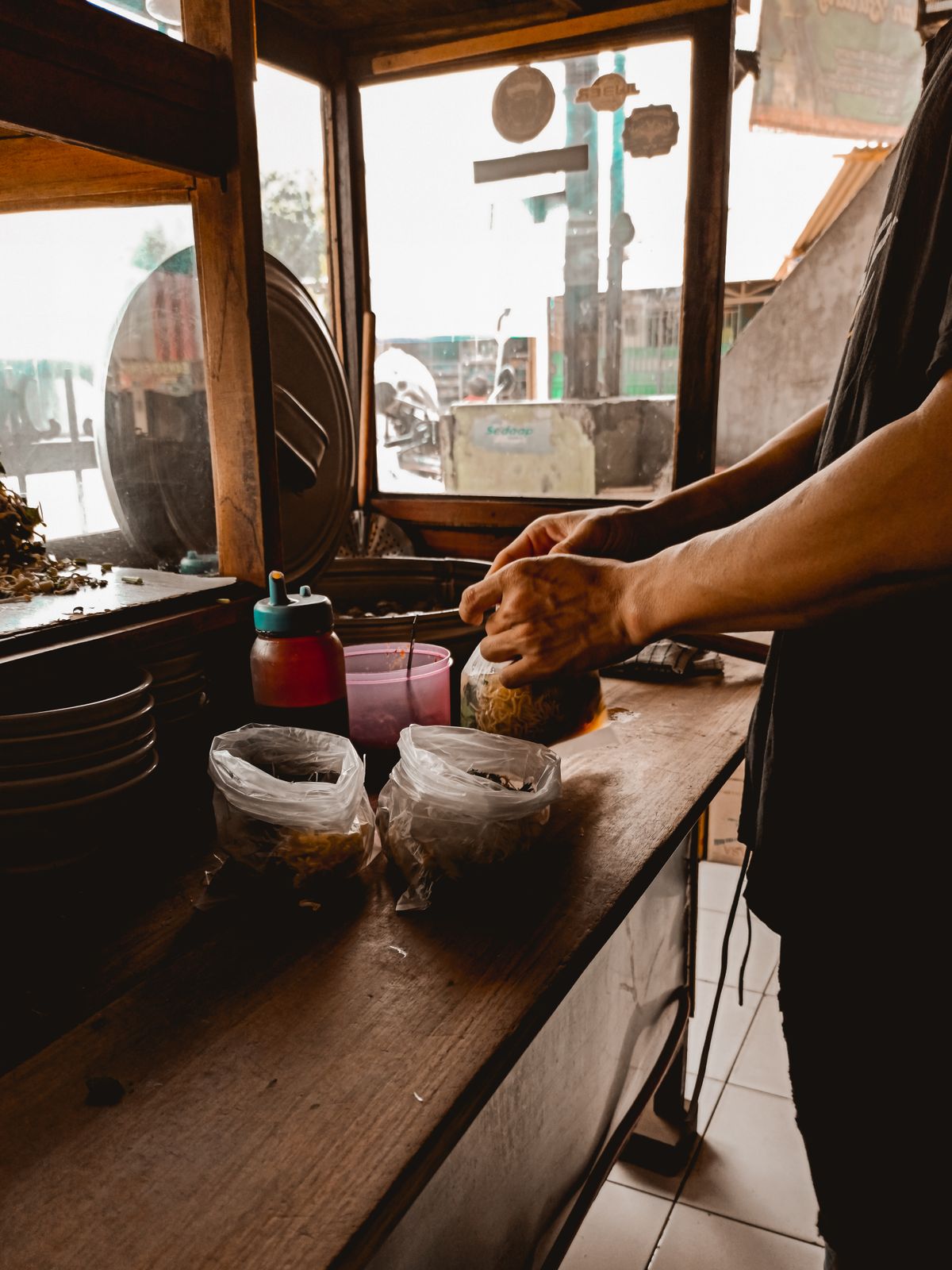 A street food vendor preparing Asian food and handing it over in a plastic bag