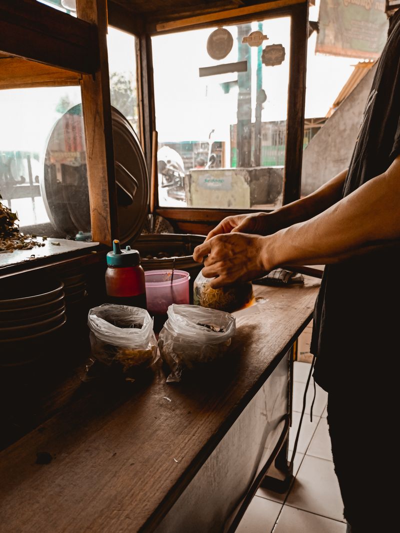 A vendor preparing fresh street food at a busy market stall