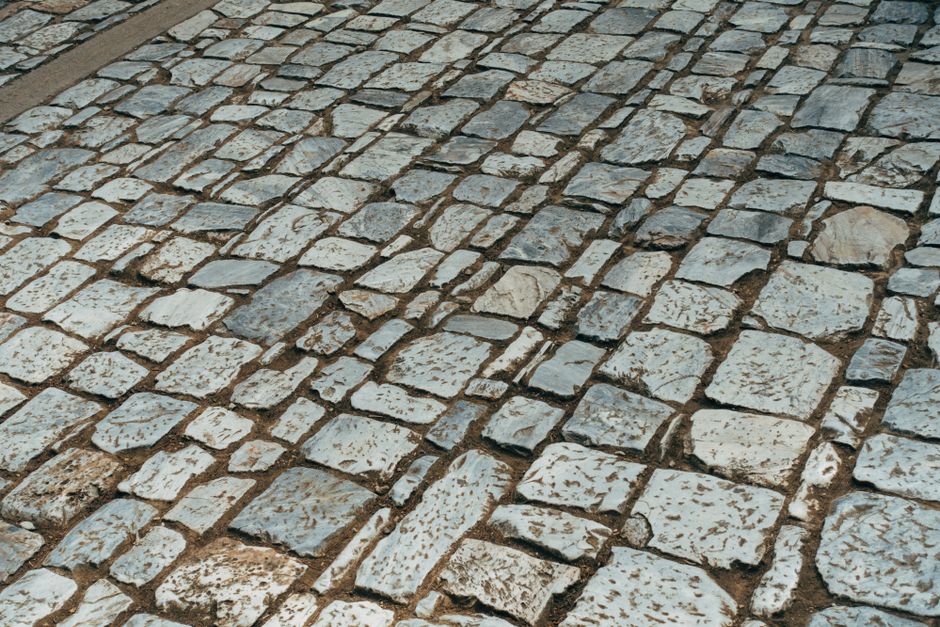 Old cobblestone path featuring granite stones in a classic pattern, offering a textured surface view.