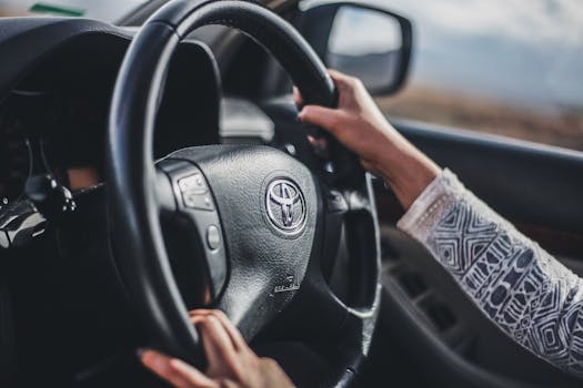 Hands gripping the wheel of a moving car, showcasing driving focus and control.