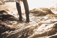 Person in Black Pants Standing on White Sand