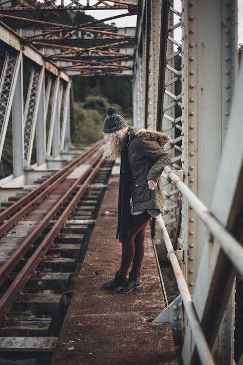 Free A Woman in Winter Clothing Leaning on a Railing Stock Photo