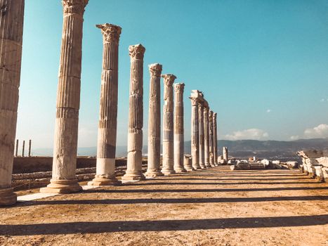 Explore majestic stone columns in ancient ruins under a clear blue sky.