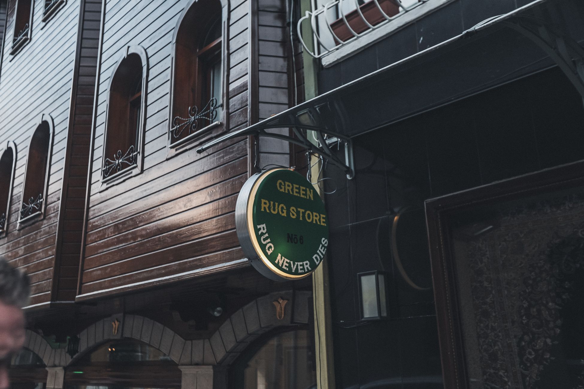 A city street featuring a wooden building facade and a rug store sign.