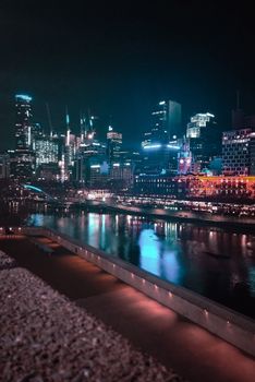 Stunning nighttime cityscape of Melbourne with skyscrapers and vibrant reflections on the water.