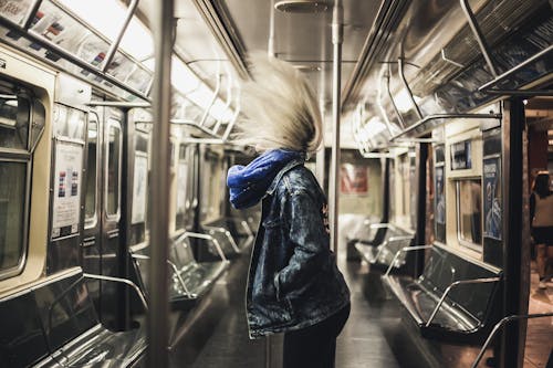 Woman in Denim Jacket Standing inside a Train
