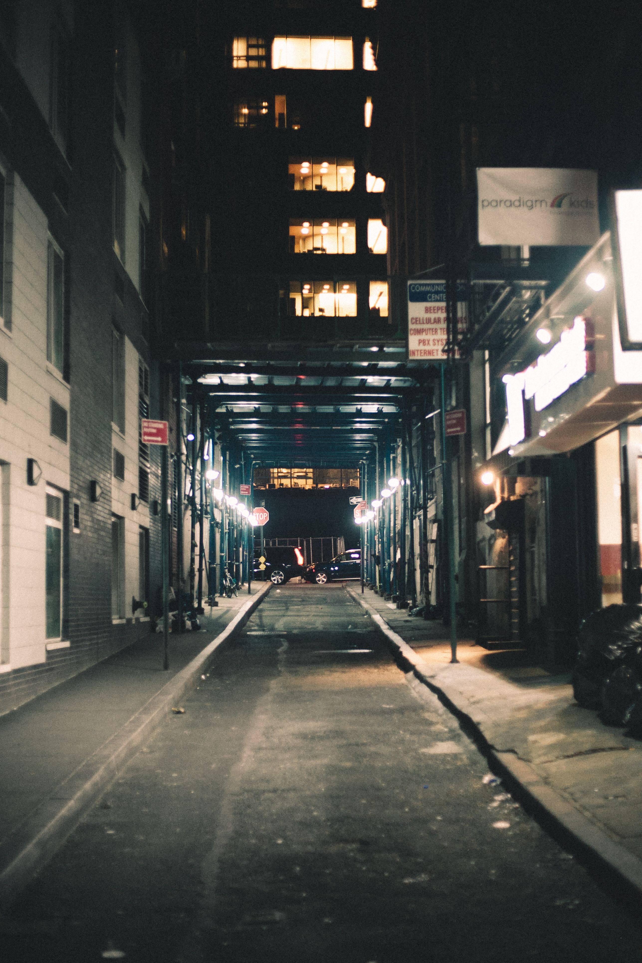 城市小巷的夜间灯光昏暗，霓虹与路灯闪烁，营造出一种喜怒无常的氛围
