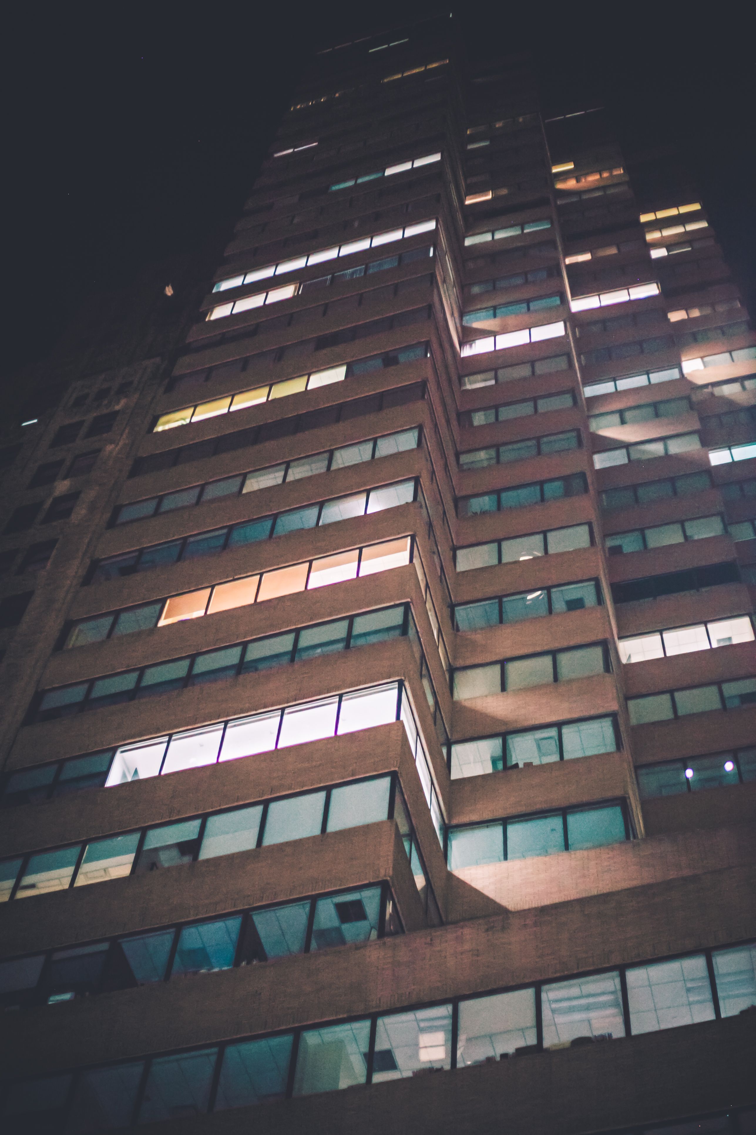夜间，低角度镜头拍摄的高层建筑窗户明亮