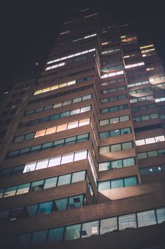 夜间，低角度镜头拍摄的高层建筑窗户明亮