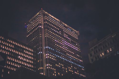 Free A nighttime view of a skyscraper with glowing windows, creating an urban cityscape ambiance. Stock Photo