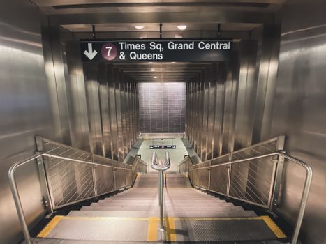 Descending stainless steel stairs leading to Times Square subway platform in New York City.