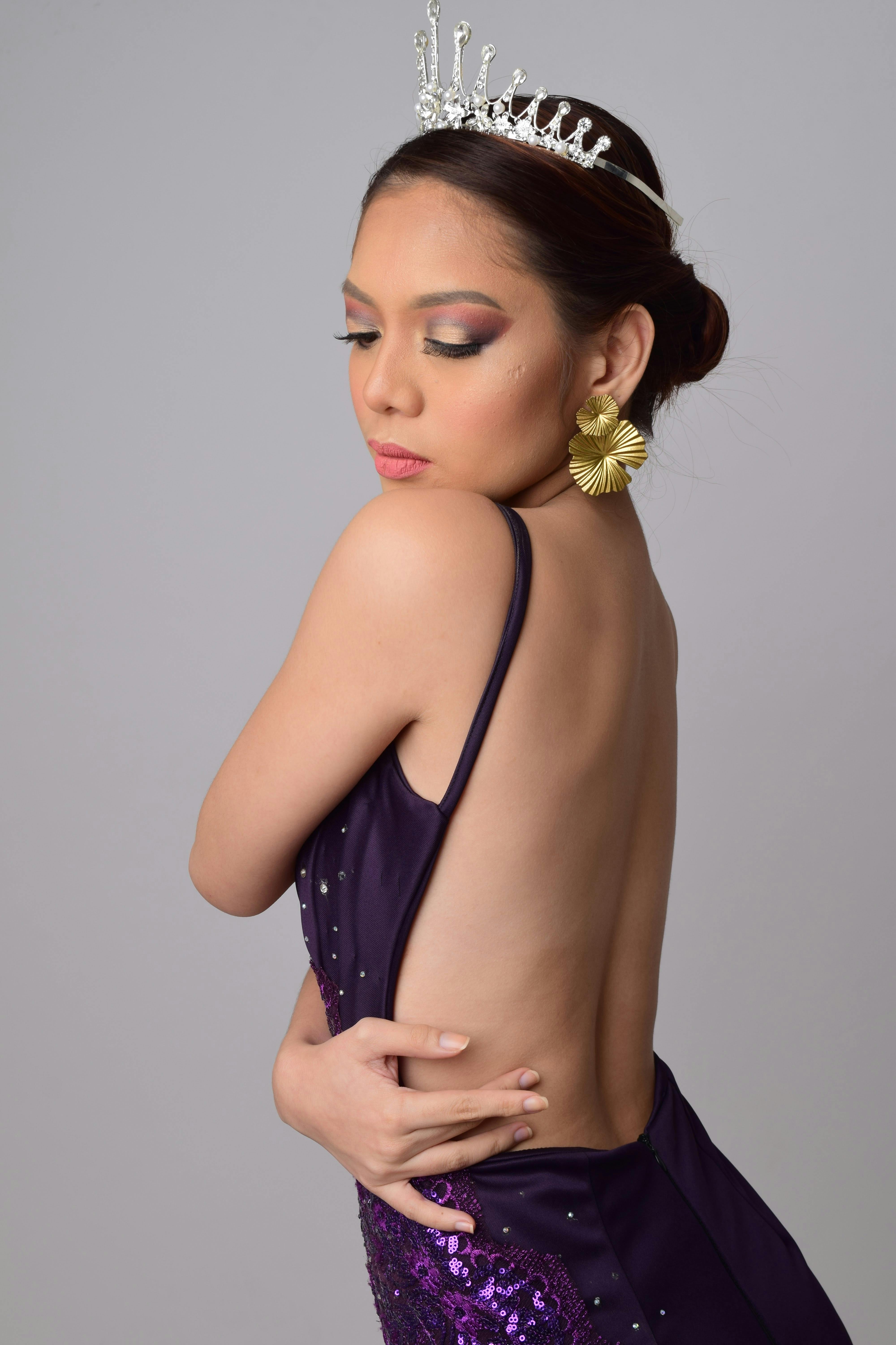 Sophisticated portrait of a woman in a purple gown and tiara, showcasing elegance.