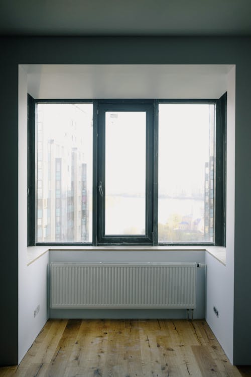 Free Wide transparent rectangular window and simple radiator in enclosed balcony with furniture in daytime Stock Photo