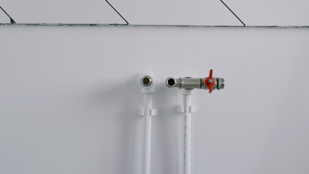 Exposed supply pipes running up the wall of an empty room