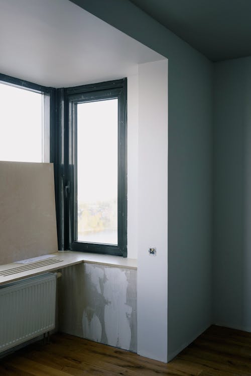 Long rectangular transparent window with thin black frame in bright room with white walls in new building