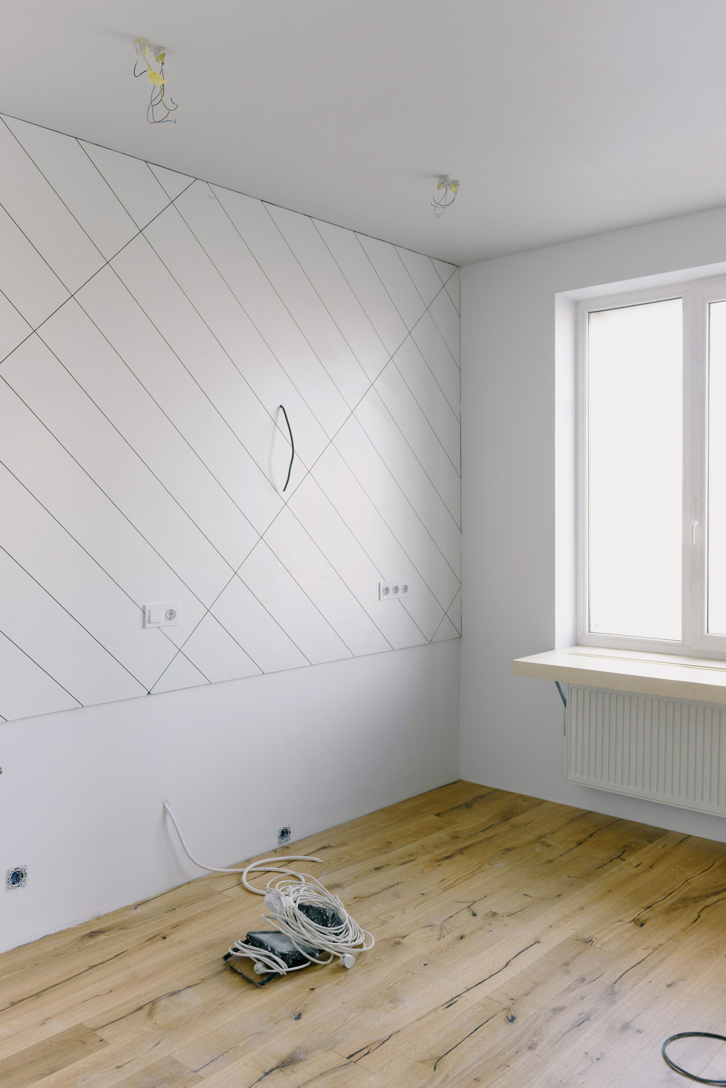 Séjour vide et nettoyé, parquet clair et murs blancs, lumière naturelle entrant par une haute fenêtre.