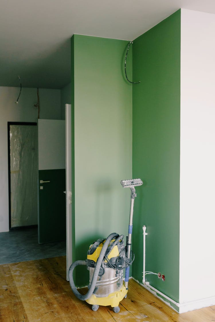 Vacuum Cleaner In Corner Near Green Wall