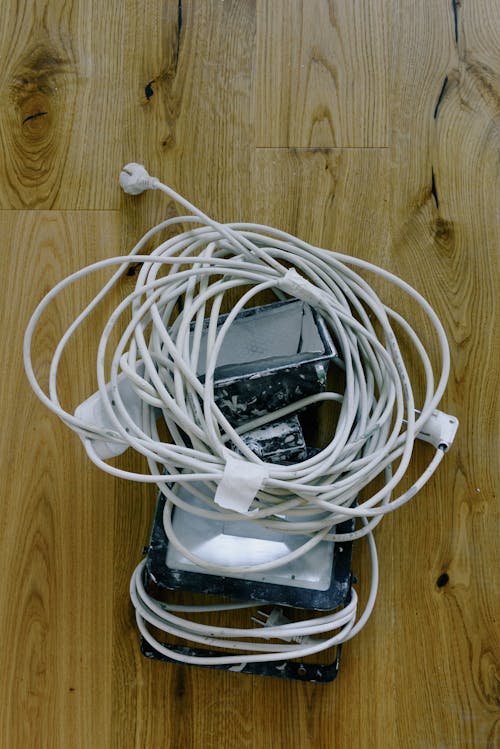 Top view of electrical white cord with standard electrical plug power outlet placed on spotlight on wooden surface during repair